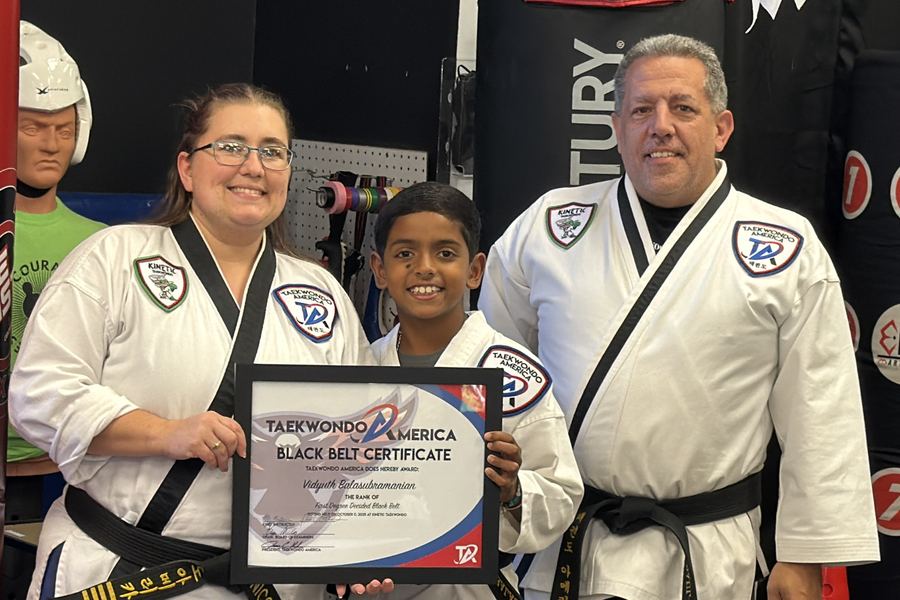 A Kinetic student receiving his first-degree black belt certificate