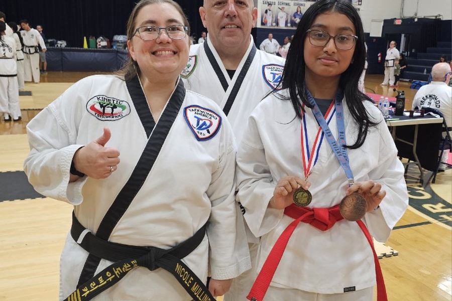 A Kinetic student with her tournament medals, alongside instructors Ms. Mullins and Mr. Paul